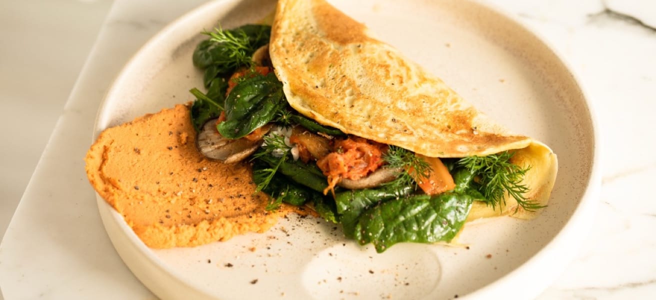 Close-up view of vegitarian omelette bursting with dill, spinach, mushrooms and tomatoes